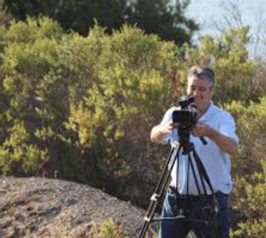 Rick Bacigalupi witih camera outdoors in CA sun on a hill